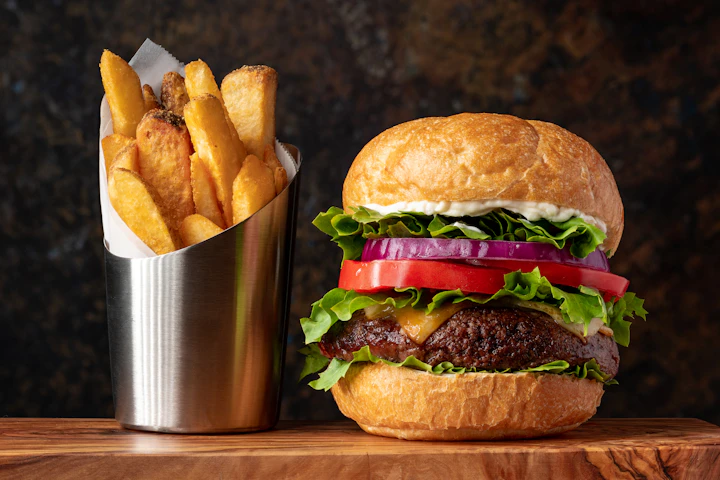 A burger with fries in a steel cup